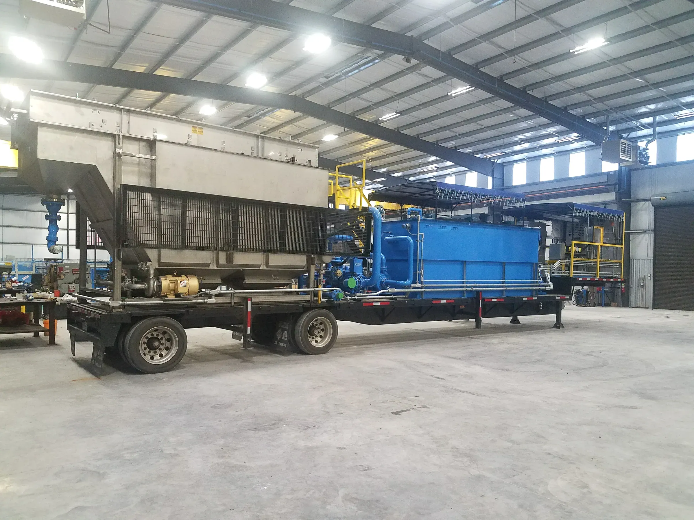 Trailer-mounted stainless clarifier and blue DAF unit under assembly inside a Spectrum fabrication shop