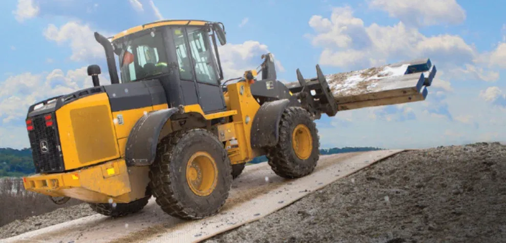 Wheel loader carrying timber mats across a composite mat roadway