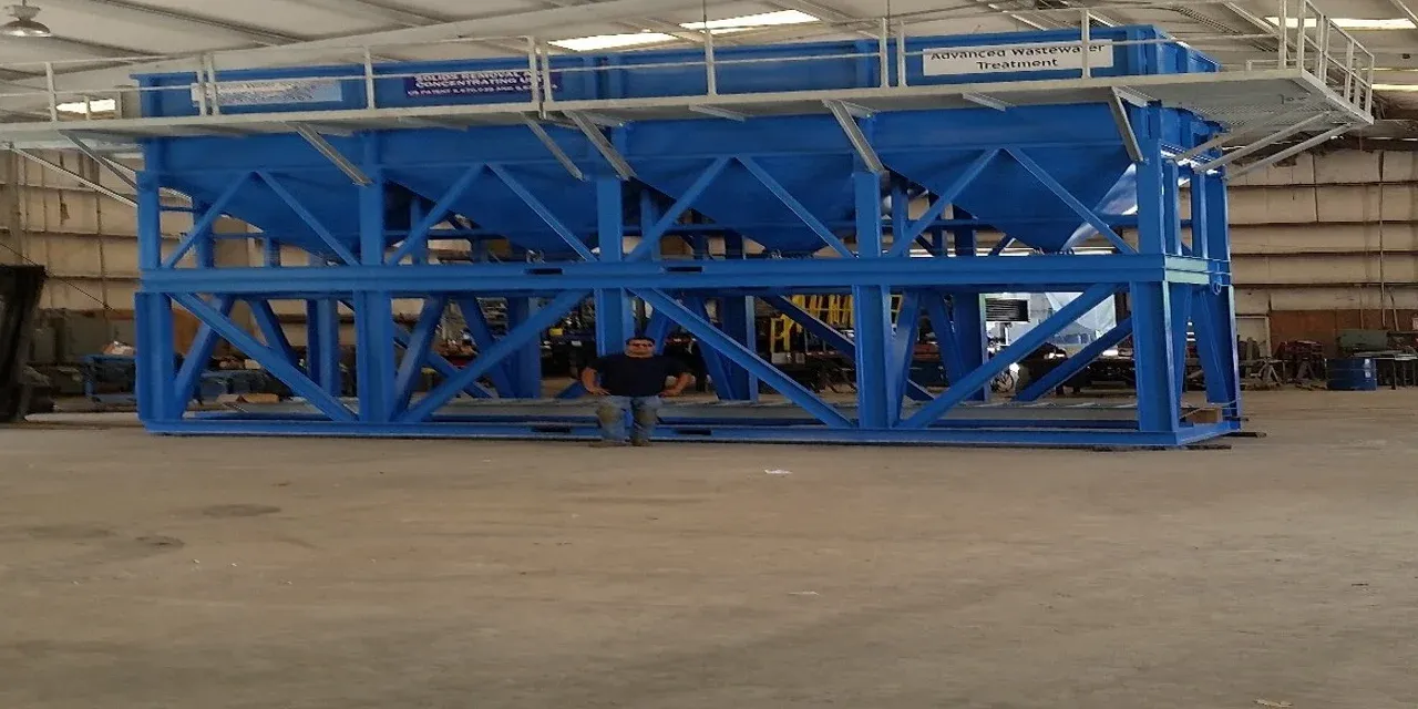 Blue skid-mounted mobile clarifier with cone bottoms and elevated catwalk in the fabrication shop